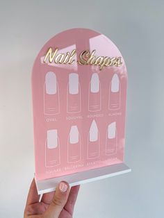 a person holding up a pink display case with nail shapes on the front and sides