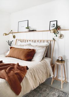 a bed with white sheets and brown pillows in a bedroom next to a wooden table