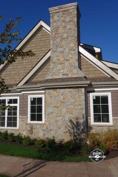 a house with a stone chimney and white windows