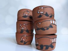 four brown and black pots with animals painted on them