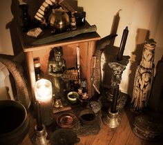 an assortment of candles and statues on a table