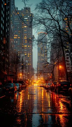 a city street at night with cars parked on the side and buildings in the background