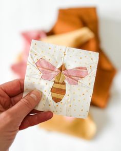 a hand holding up a piece of paper with a bee on it's side