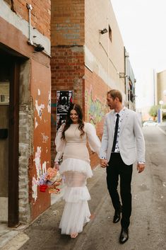 a man and woman walking down the street holding hands