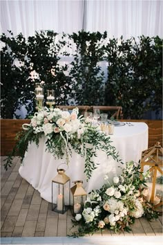 the table is set with candles, flowers and greenery for an outdoor wedding reception