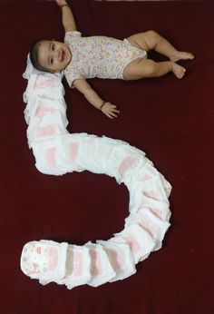 a baby laying on top of a red blanket next to a white and pink snake