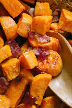 roasted sweet potatoes with bacon and spices in a wooden serving bowl next to a spoon