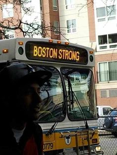 a man standing in front of a bus with boston strong written on it's side