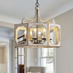 a chandelier hanging from the ceiling in a room with white walls and windows