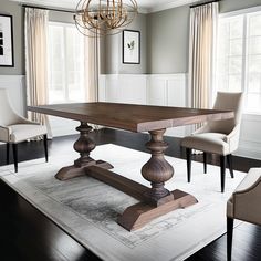 a dining room table and chairs in front of two large windows with chandeliers