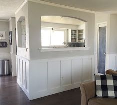 a living room with white paneling and wood floors