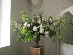 a vase filled with flowers sitting on top of a wooden box next to a mirror