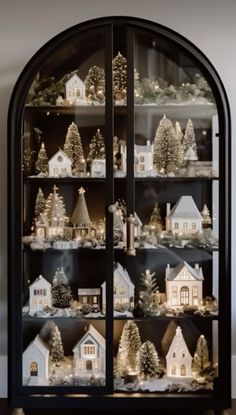 a lighted display case filled with lots of christmas trees and small white houses in it