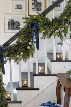 christmas decorations on the banisters and stairs in a home with pictures hanging above them