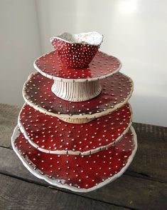 a stack of red and white plates sitting on top of a wooden table