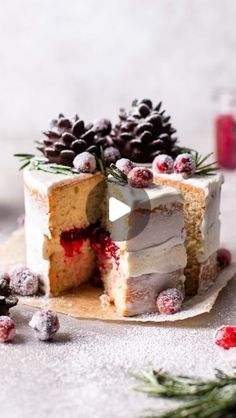 a white cake with pine cones and berries on top is cut in half to show the inside