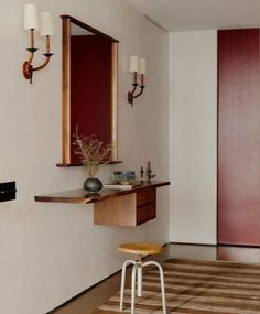 a bathroom with a vanity, mirror and stool next to a wall mounted faucet