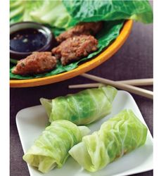 lettuce wraps with meat and dipping sauce on a plate next to chopsticks