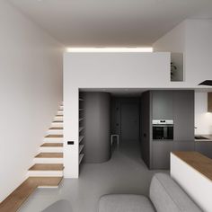 a living room filled with furniture next to a kitchen and staircase leading up to the top floor