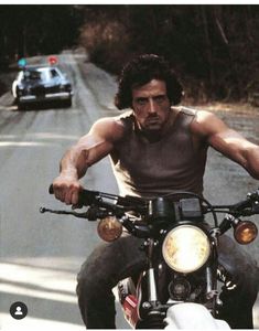 a man riding on the back of a motorcycle next to a car in front of him