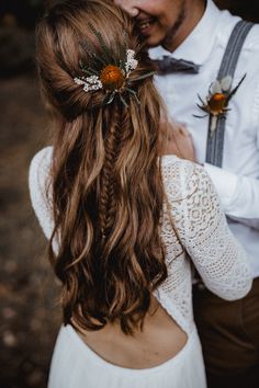 a man and woman standing next to each other with flowers in their hair wearing suspenders