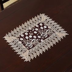 an embroidered table runner on top of a wooden table