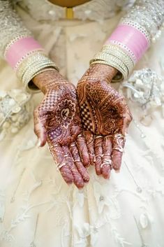 the brides hands are decorated with hennap and bracelets on her wedding day