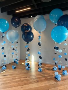 blue and white balloons floating from the ceiling in an empty room with wood flooring