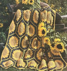 a crocheted blanket with sunflowers on the ground in front of it