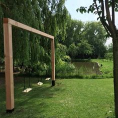 an empty soccer goal in the middle of a grassy field next to a pond and trees