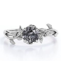 a white gold ring with black diamonds and leaves on the band, set in 18k white gold