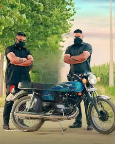 two men standing next to a motorcycle on a dirt road