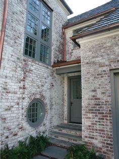 a brick house with an arched window and stone steps leading up to the front door