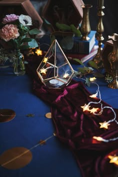 a table topped with candles and vases filled with flowers on top of a blue cloth