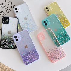 four iphone cases with glitter on them sitting on top of a white table next to each other