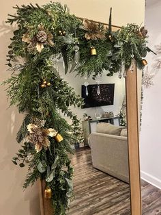 a mirror decorated with greenery and gold ornaments in a living room area at home