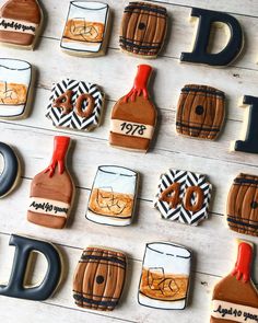 decorated cookies are arranged in the shape of whiskey bottles and barrels on a white table