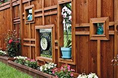 a wooden fence with flower pots and plants on it's sides, along with a clock