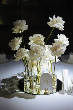 white flowers in a glass vase on a table with place cards and napkins around it