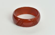 "Info: ♥ Circa: 40s ♥ Label: None ♥ Color: Sienna ♥ Material: Bakelite ♥ Condition: Very good vintage condition. Light surface wear and faint scratches appropriate with age. Details: ♥ Lovely versatile medium carved bakelite bangle ♥ Sienna color, a reddish brown ♥ Domed shape ♥ Translucent clarity ♥ Tested positive for bakelite using the Simichrome test ♥ A wonderful piece to wear alone or in combination with other bakelite bangles! Measurements: Width: 1\" Wall thickness: .25\" Inside across: Elegant Brown Bangle For Formal Occasions, Elegant Formal Brown Bangle, Vintage Carved Bangle For Wedding, Vintage Carved Bracelet For Wedding, Elegant Bakelite Bracelet Jewelry, Elegant Bakelite Bracelet, Vintage Intaglio Bracelets For Formal Occasions, Vintage Bakelite Bangle Jewelry, Vintage Bakelite Bangle