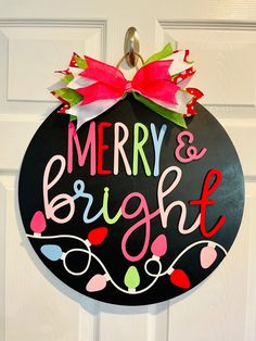 a merry and bright christmas ornament hanging on a door with a red bow