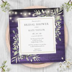 a purple and white wedding shower card with greenery on it, surrounded by string lights