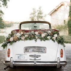 an old white car with flowers on the back