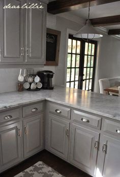 a kitchen with white cabinets and marble counter tops in the center is an open window