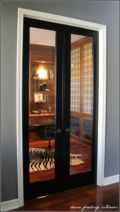 an empty room with two black doors and a zebra rug on the floor in front of it