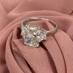 an engagement ring sitting on top of a pink cloth