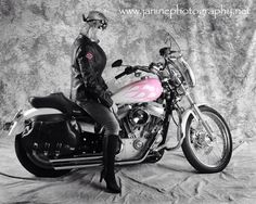 black and white photograph of a woman sitting on a motorcycle with pink painted side panels