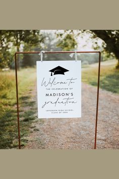 a sign that is on the side of a dirt road with trees in the background