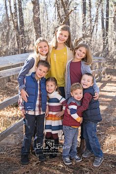 a group of young children standing next to each other in front of a wooden fence