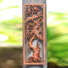 an intricate carved wooden panel with a tree on it's side and leaves in the background